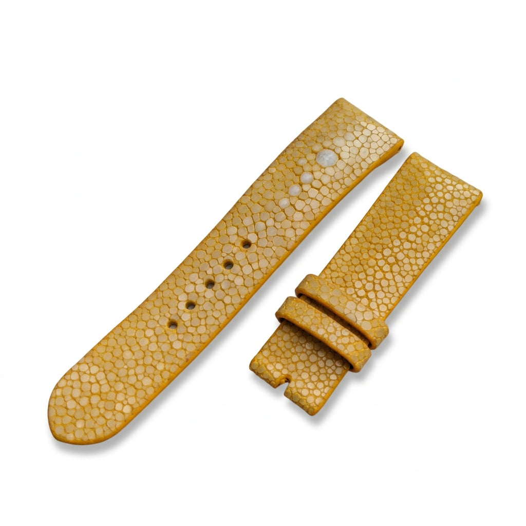 Yellow textured stingray watch strap on a wooden surface with a blurred natural background