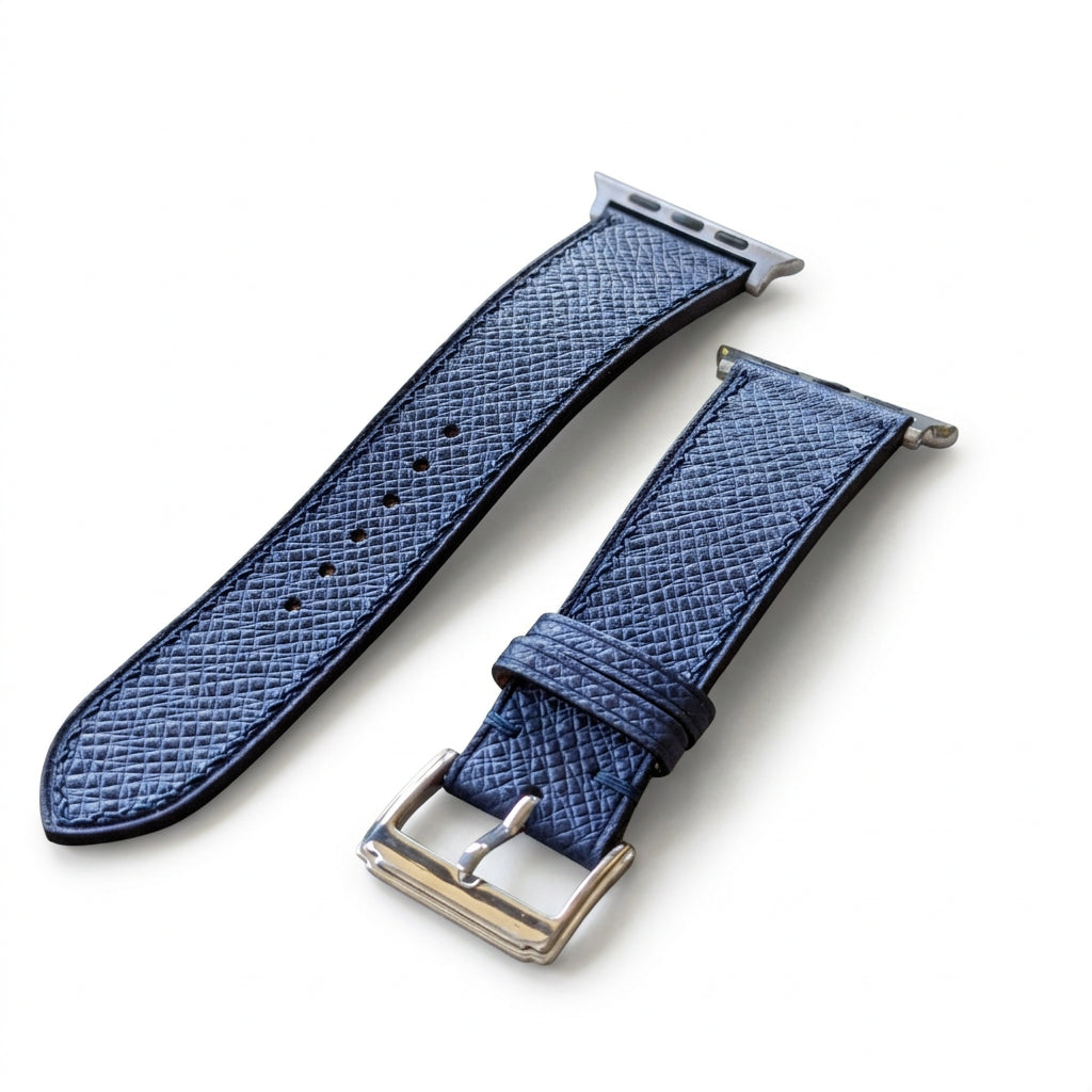 Two blue watch straps on a textured surface with blurred background