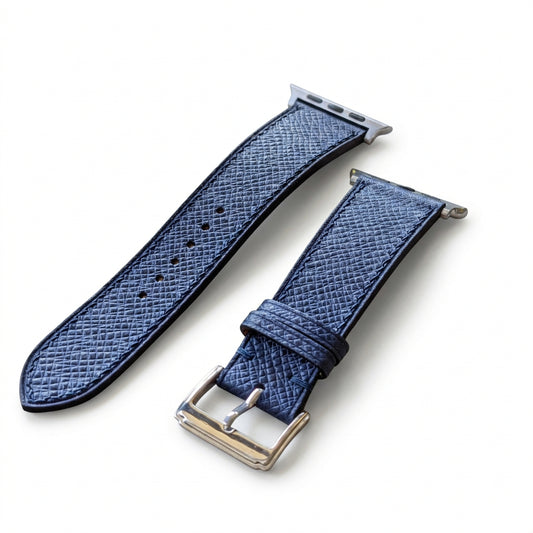 Two blue watch straps on a textured surface with blurred background